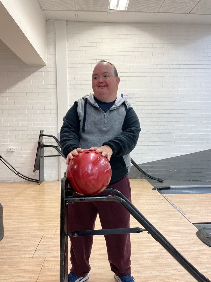 a man holding a bowling ball on a cart