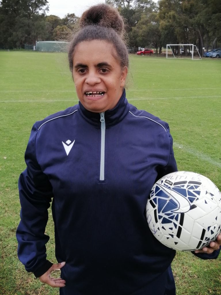 a woman holding a soccer ball on a field