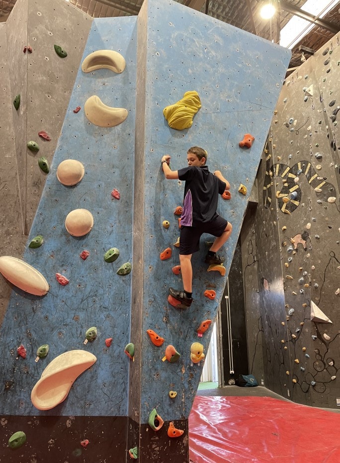 a man climbing up the side of a climbing wall