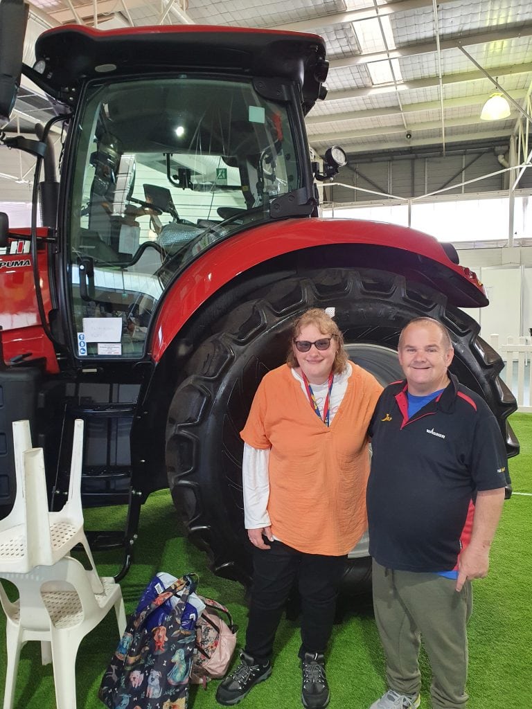 a man and a woman standing in front of a tractor