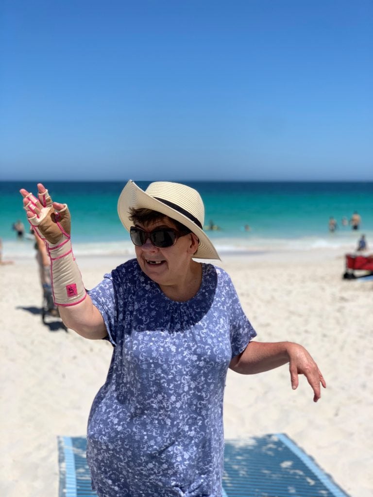 a woman in a hat and sunglasses on a beach