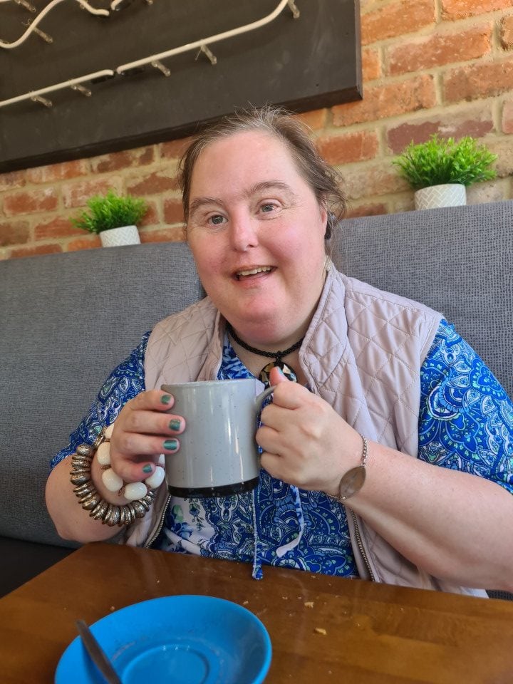 a woman sitting at a table with a cup of coffee