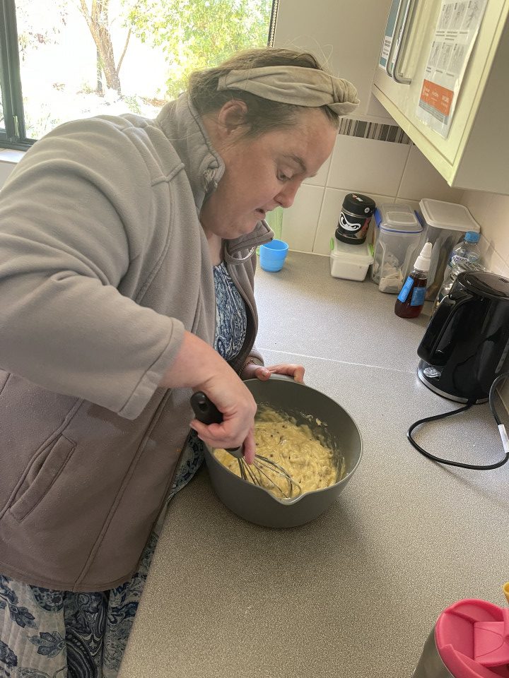 a woman in a kitchen stirring a bowl of macaroni and cheese