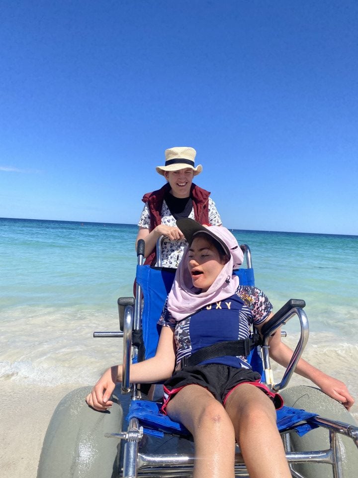 a woman sitting in a beach wheel chair next to a man