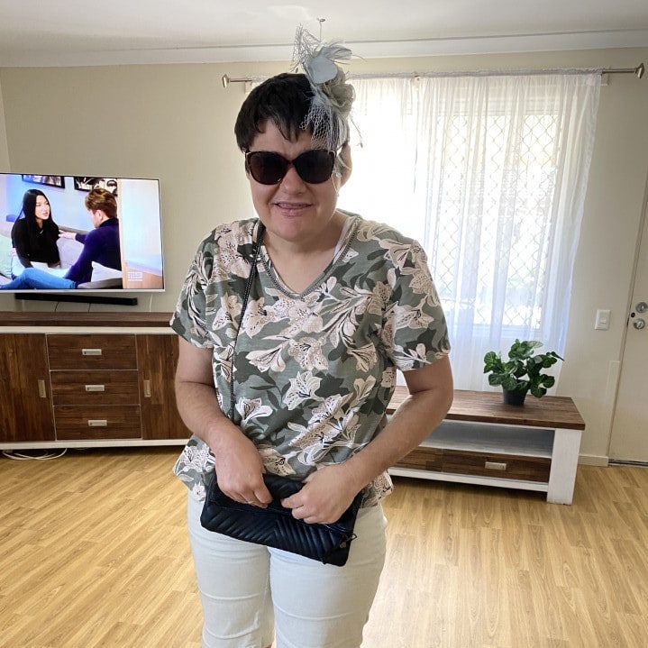 a woman standing in a living room holding a purse