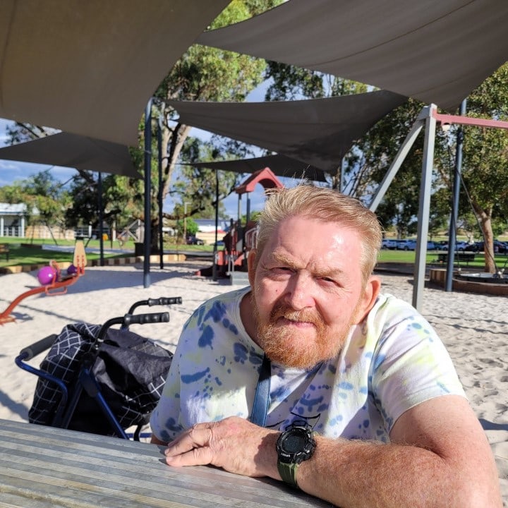 a man sitting at a picnic table in a park