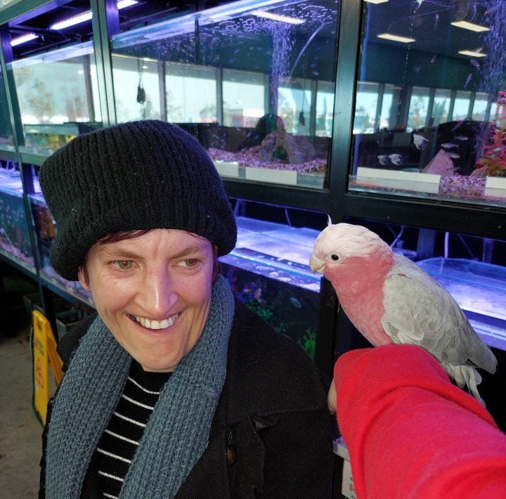 a woman holding a bird in front of a fish tank