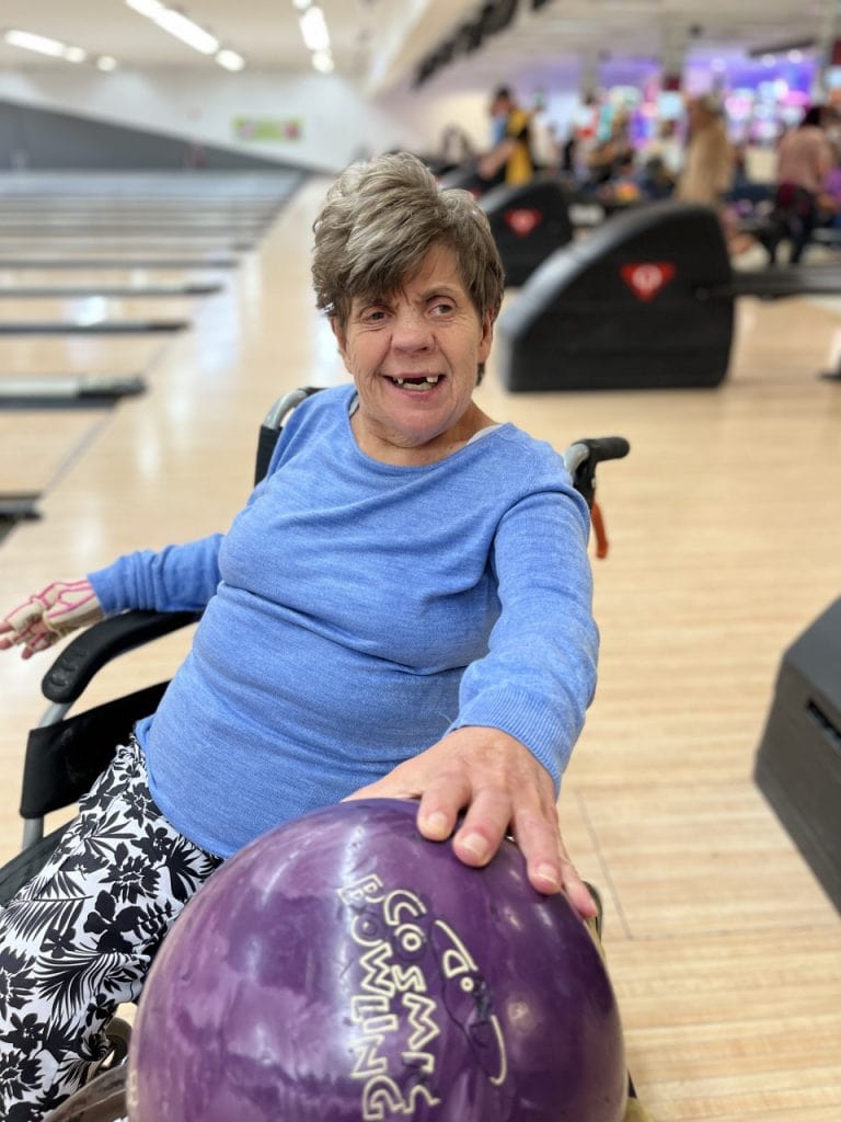a woman in a wheel chair holding a bowling ball