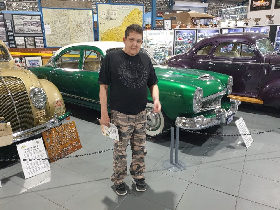 a man standing in front of a green car