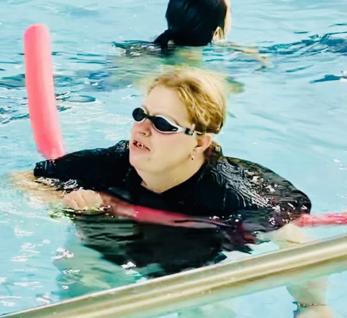 a woman swimming in a pool with a paddle