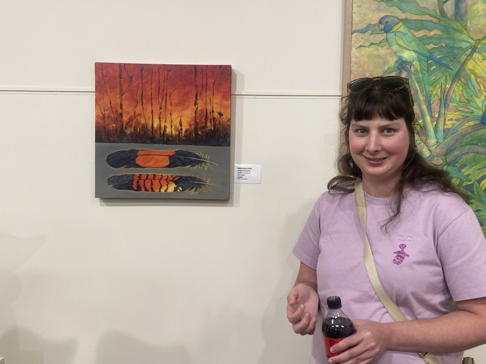 a woman standing in front of a painting holding a bottle