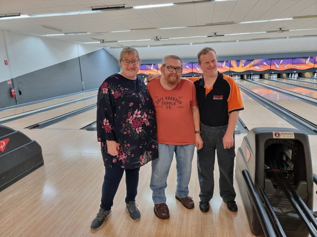 three peoples standing next to each other in a bowling alley