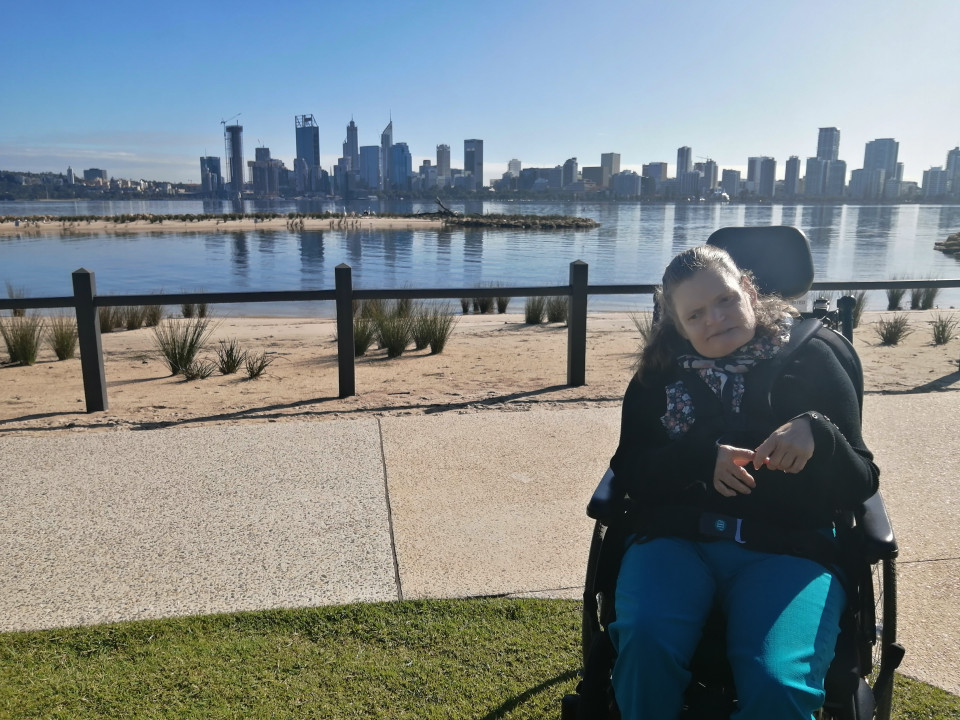 a woman sitting in a wheel chair next to a body of water