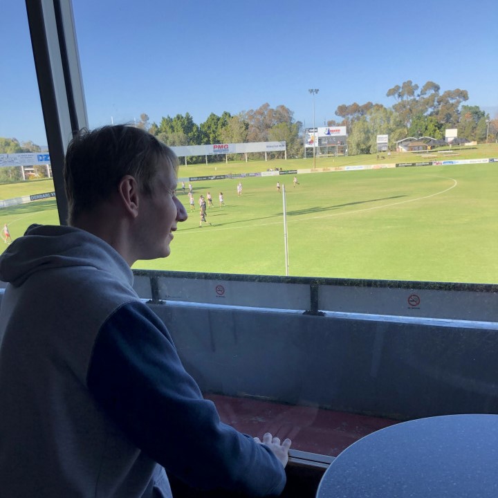 a man standing and looking looking out a window to watch football