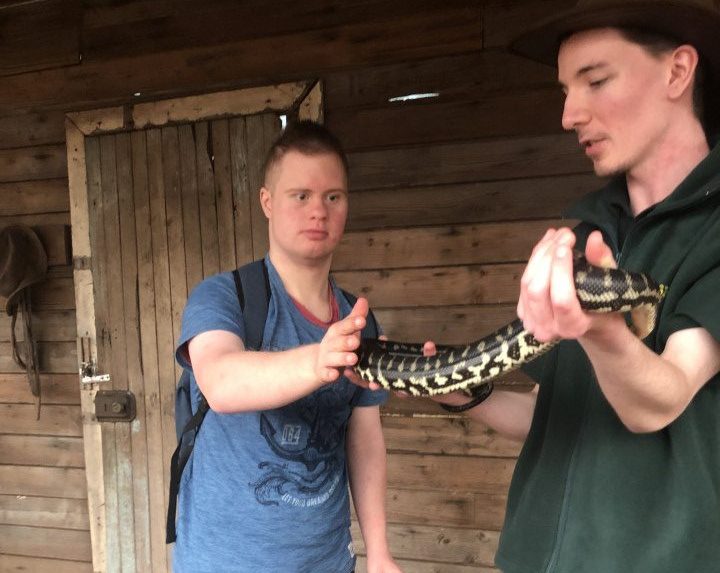 a man holding a snake in front of another man