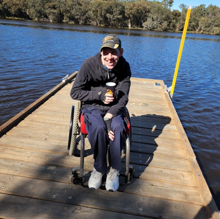 a man sitting in a wheel chair on a dock