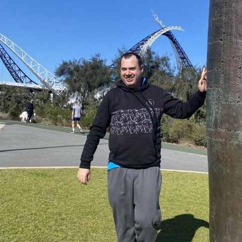 a man standing next to a tall metal pole