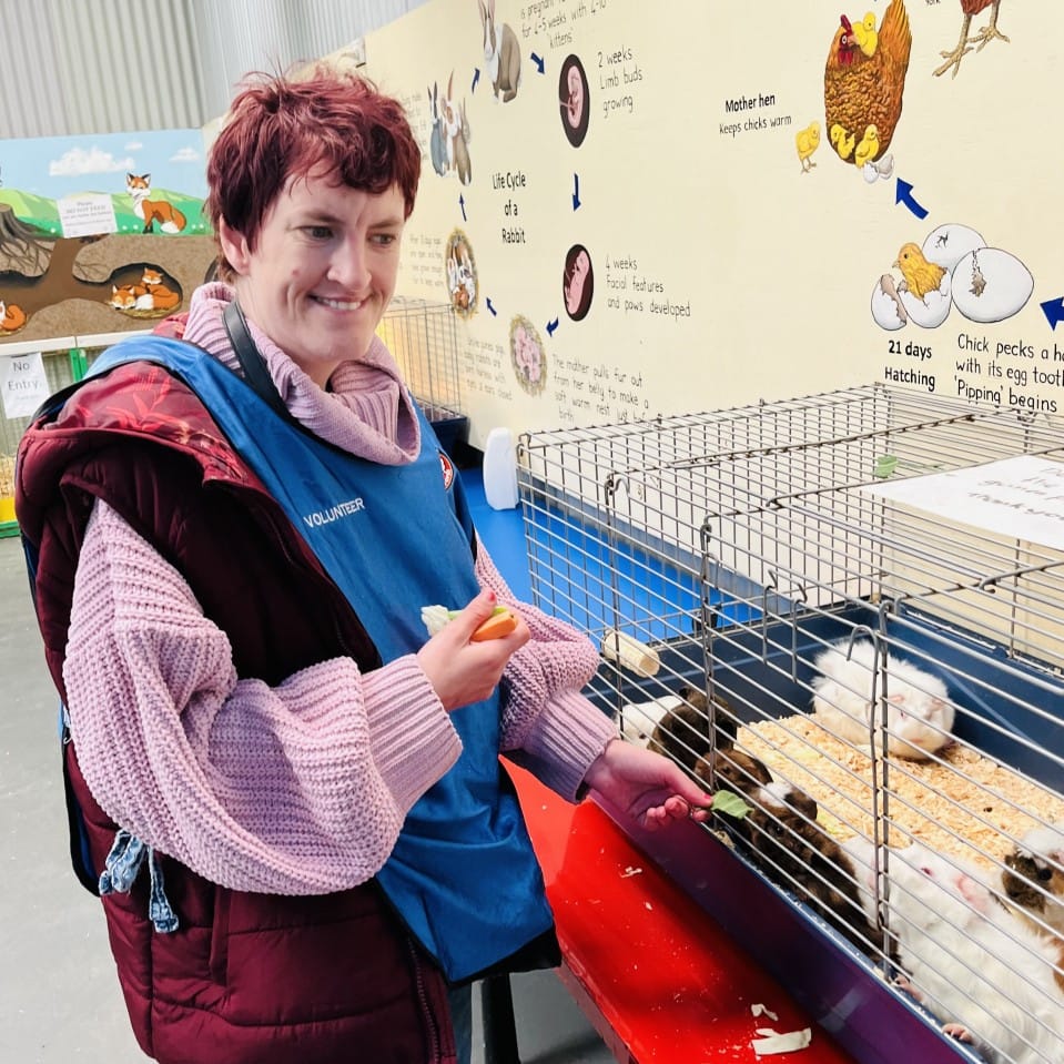 a woman standing in front of a hamster cage