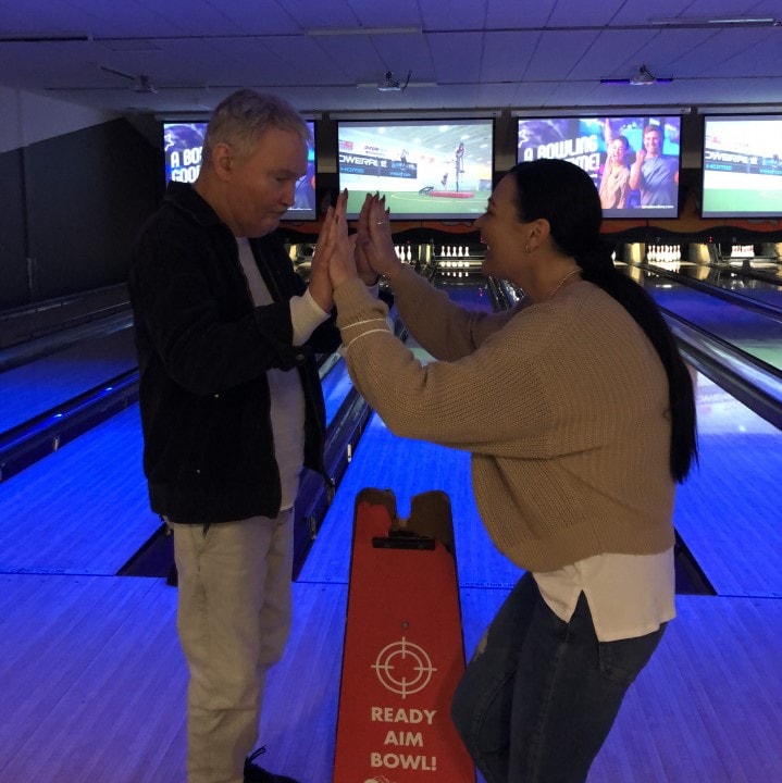a man and a woman standing in a bowling alley