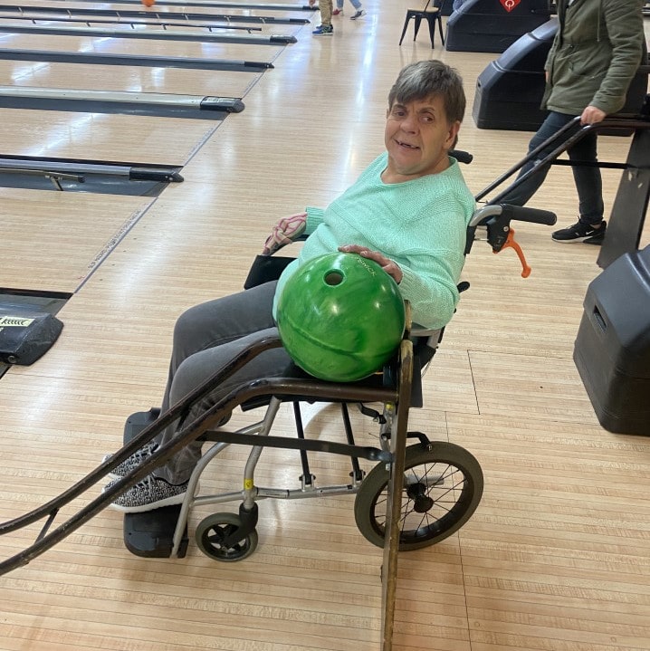 a woman in a wheel chair with a green bowling ball