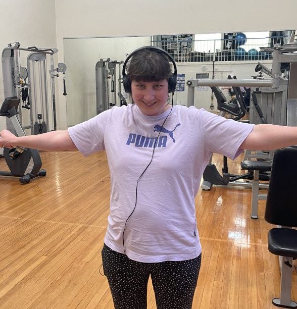 a woman standing in a gym with headphones on