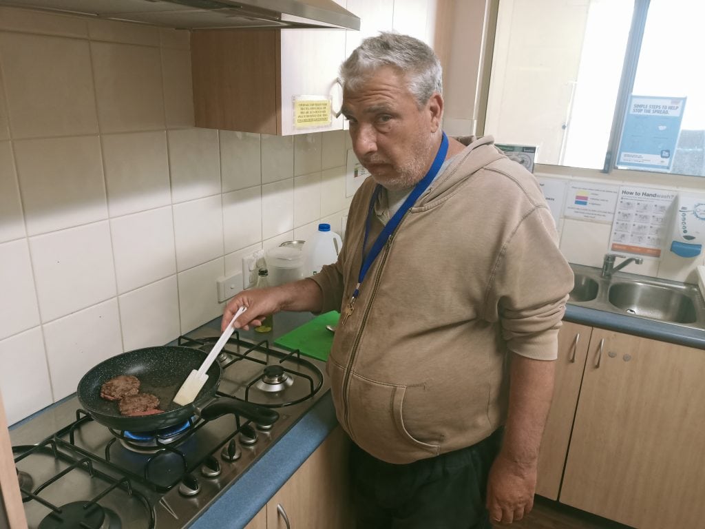 a man standing in a kitchen preparing food on top of a stove