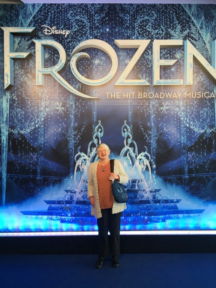 a woman standing in front of a frozen sign