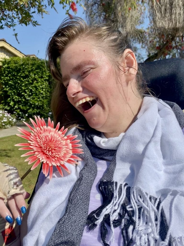 a woman laughing and holding a flower in her hand