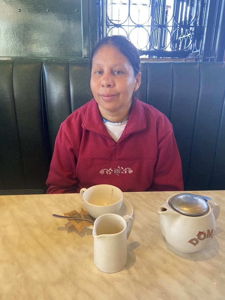 a woman sitting at a table with two cups of coffee