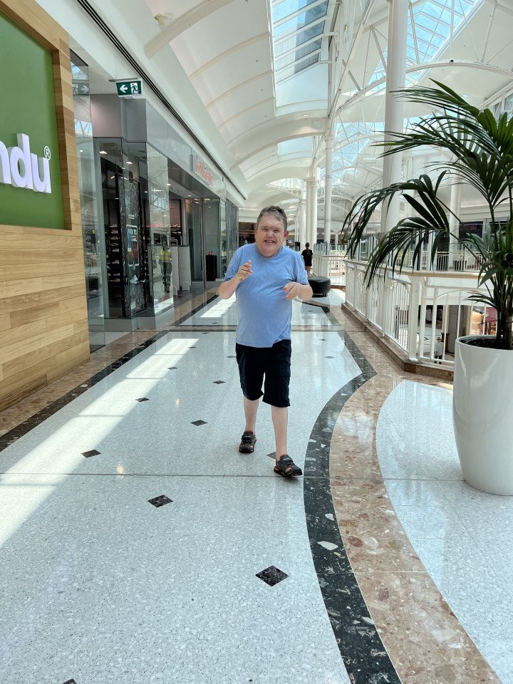 a man in a blue shirt is standing in a mall