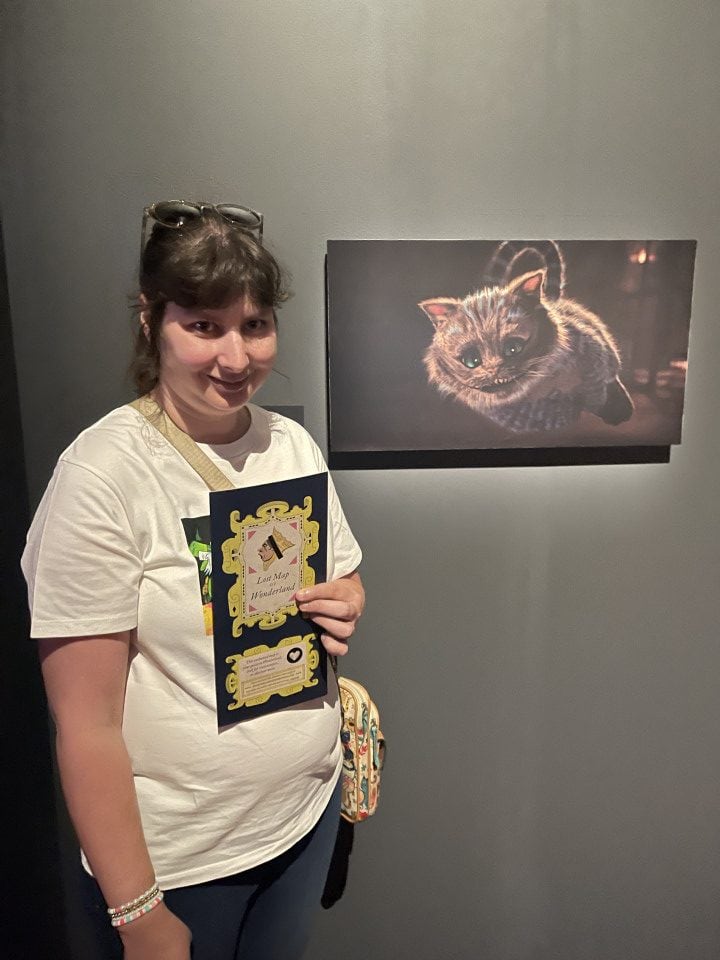 a woman standing in front of a picture of a fiction cat