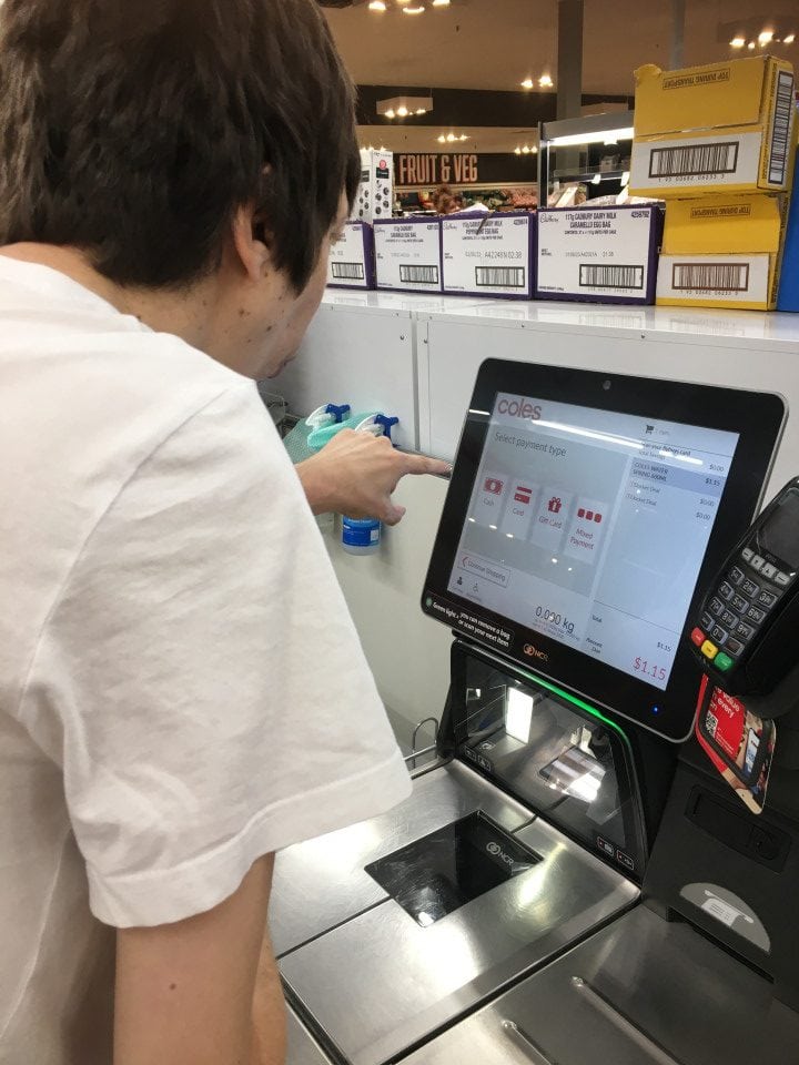 a man standing in front of a self-checkout machine