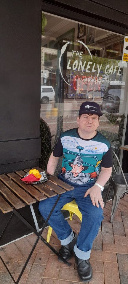 a man sitting on a bench in front of a restaurant.