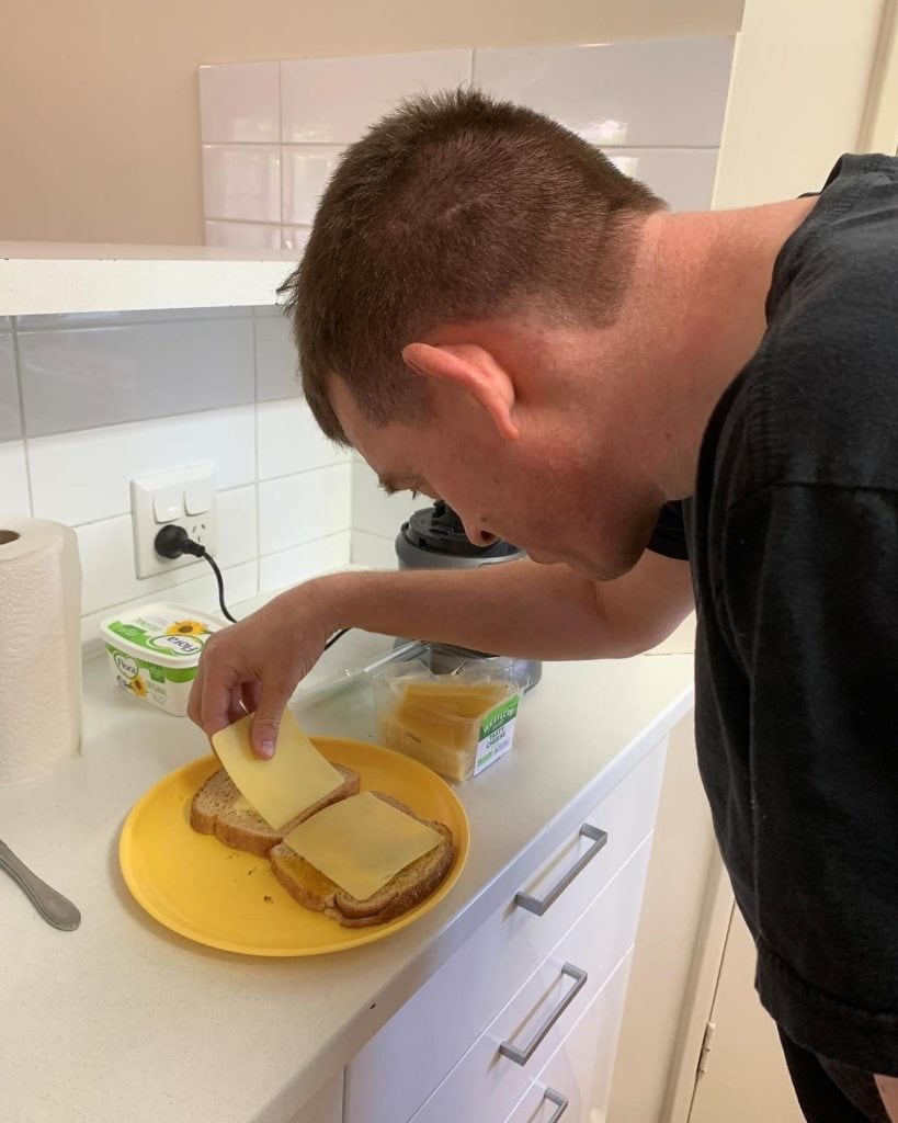 a man putting cheese on sandwich on a yellow plate.