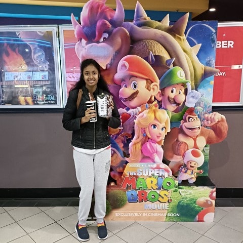 a woman standing in front of a super mario bros poster.