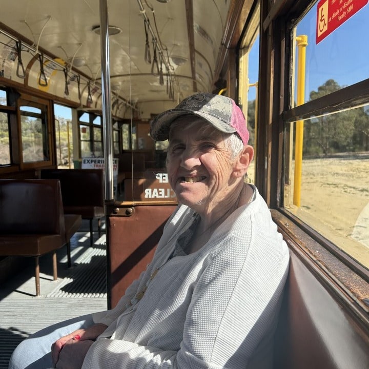 a man sitting on a tram looking at the camera with his big smiling.