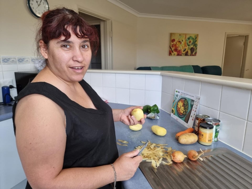 a woman standing in a kitchen preparing food.