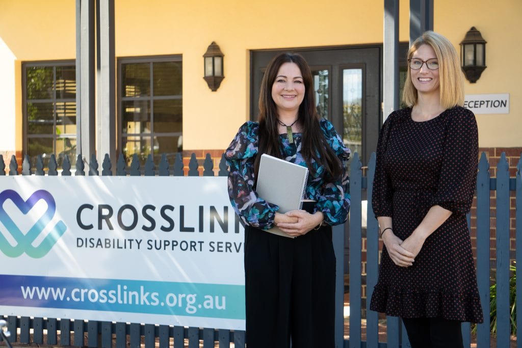 two women standing in front of a crosslink sign.